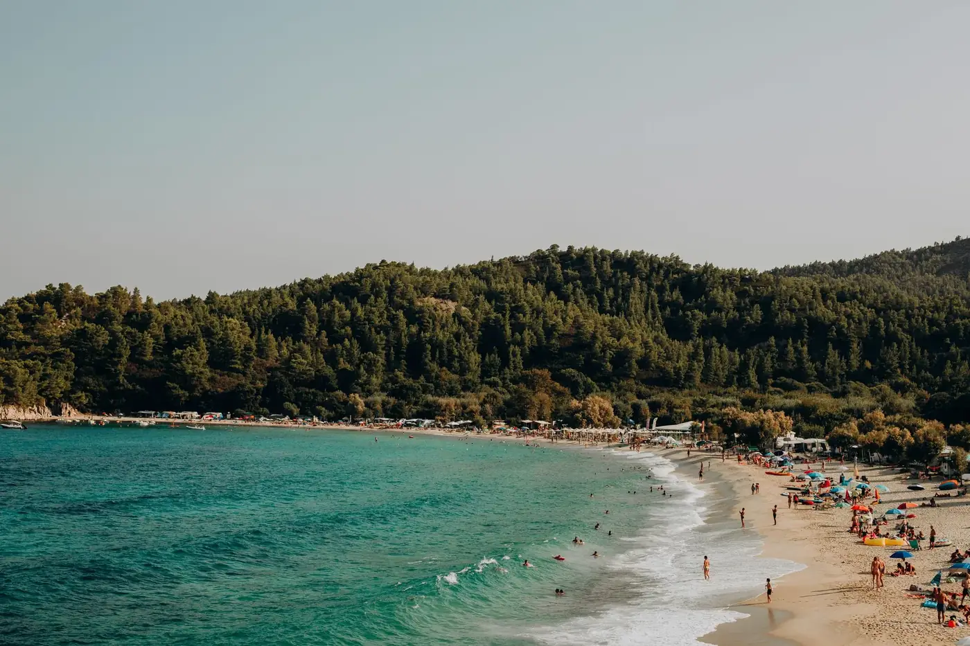 Beautiful Greek beach with people enjoying a sunny summer day by the ocean.