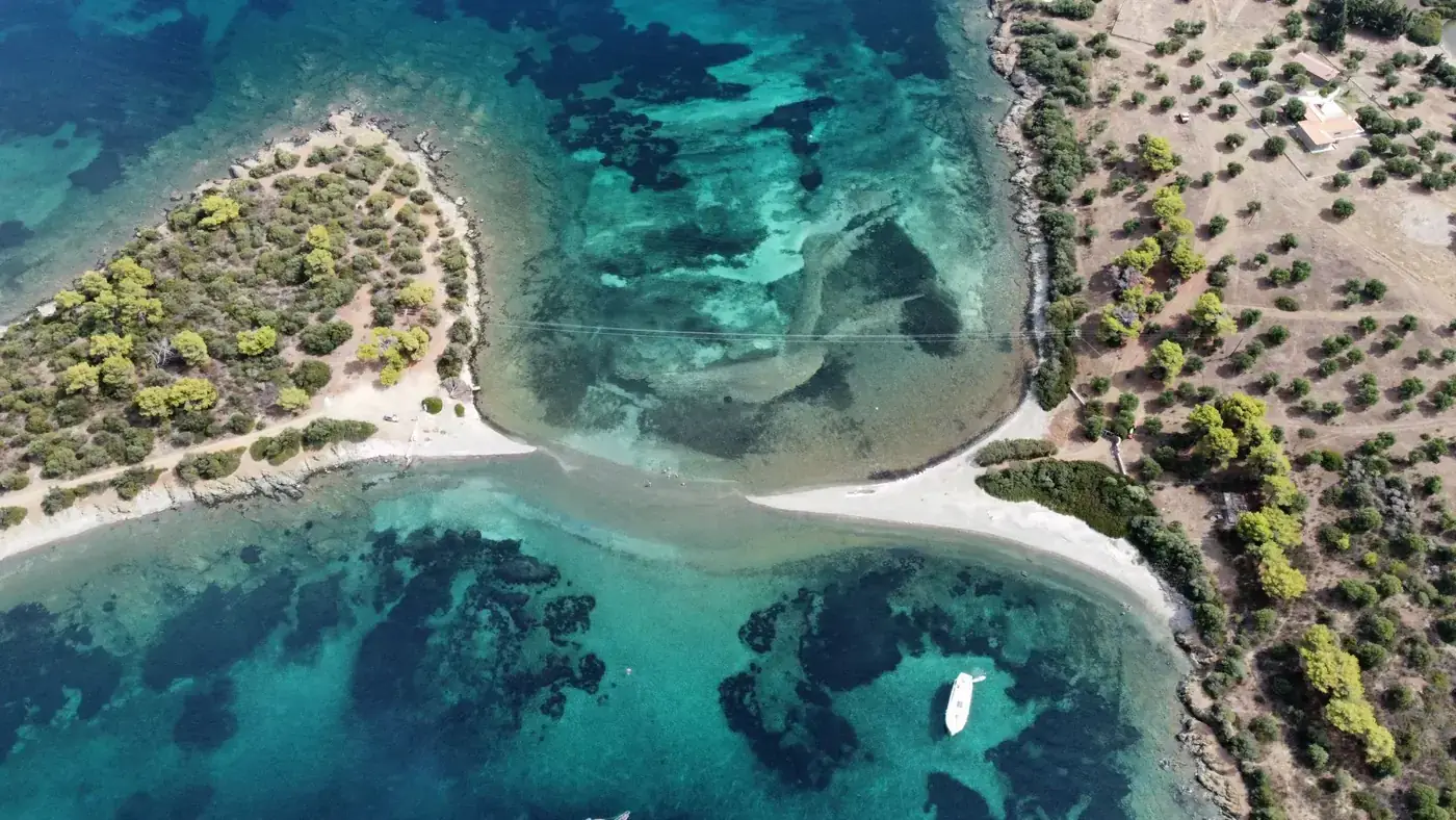 Stunning aerial view showcasing Greece's coastline with crystal-clear waters and lush greenery.