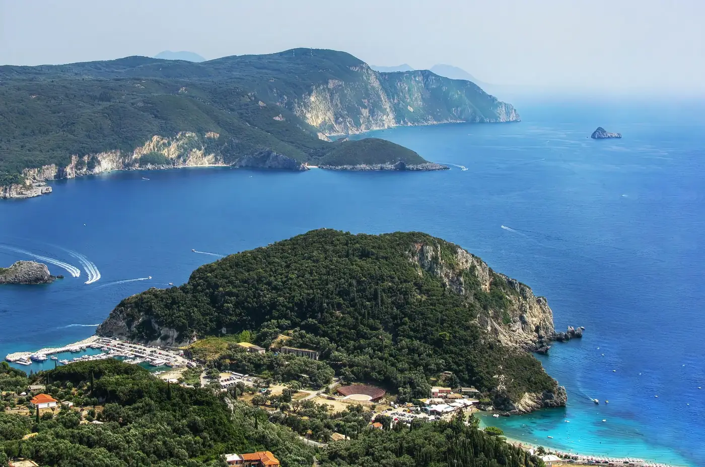 Explore the breathtaking aerial view of Corfu's lush cliffs and vibrant blue waters in Greece's Ionian Sea.