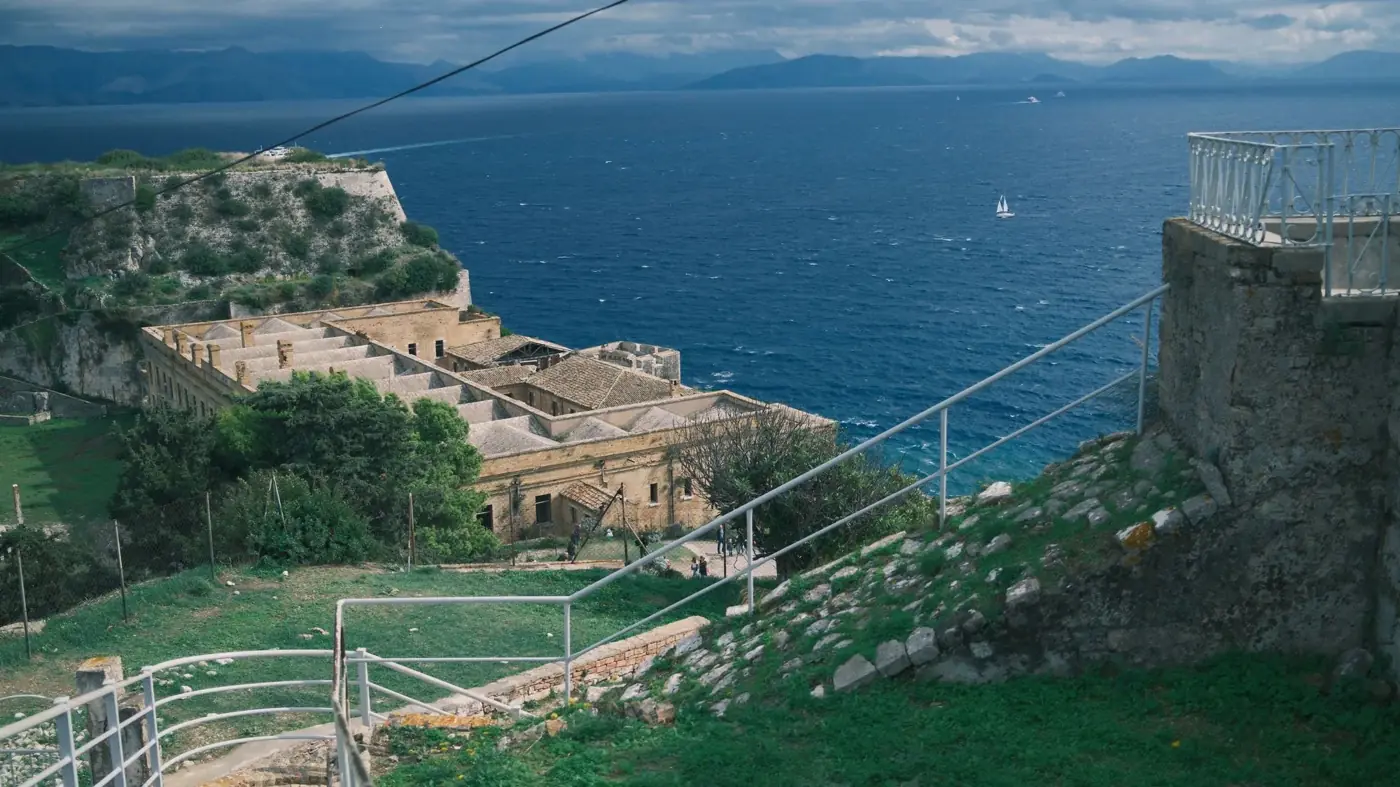 View of a historic fortress overlooking a blue sea with distant mountains.