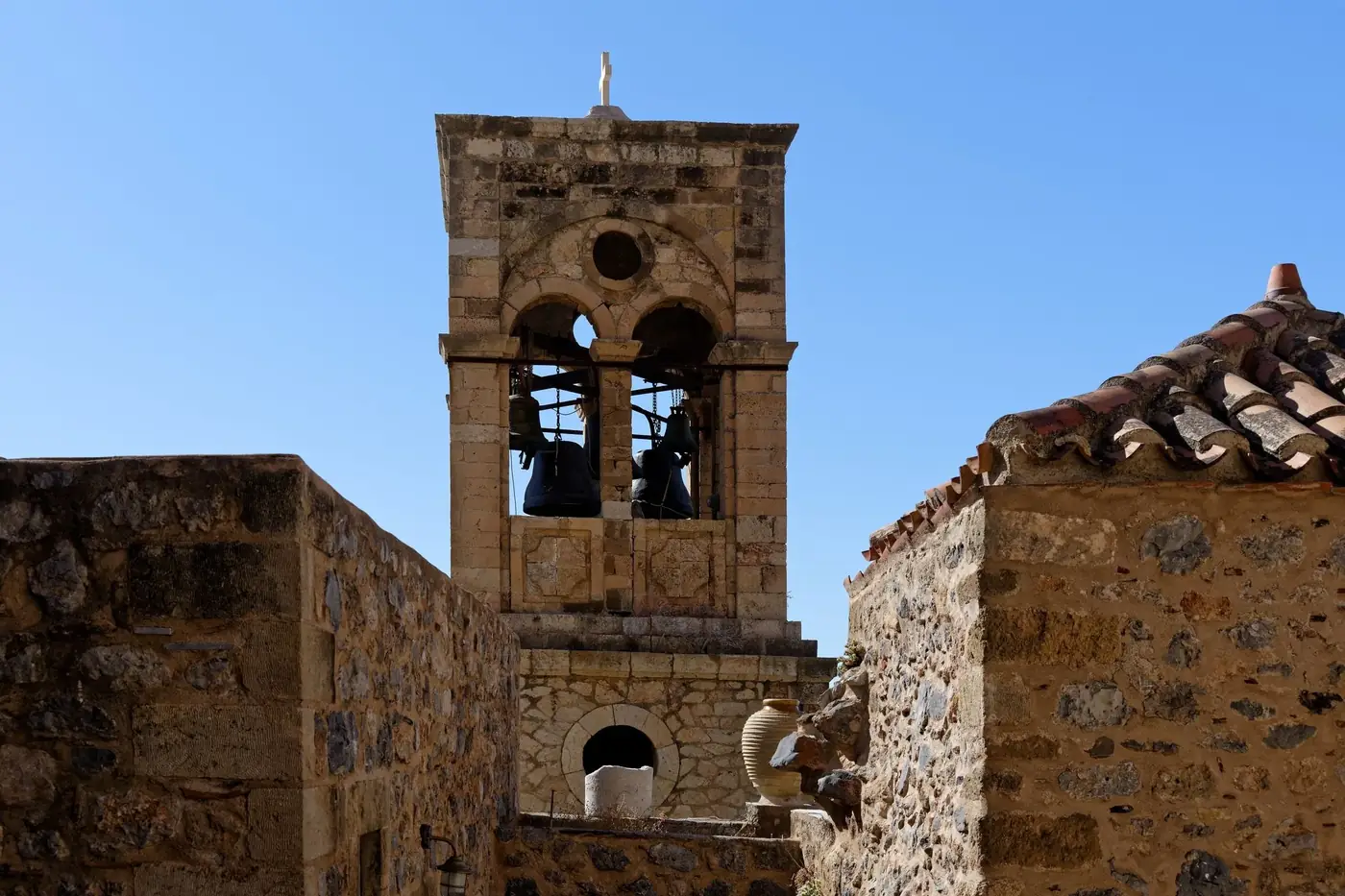 Explore the ancient stone bell tower in Monemvasia with clear blue skies overhead.