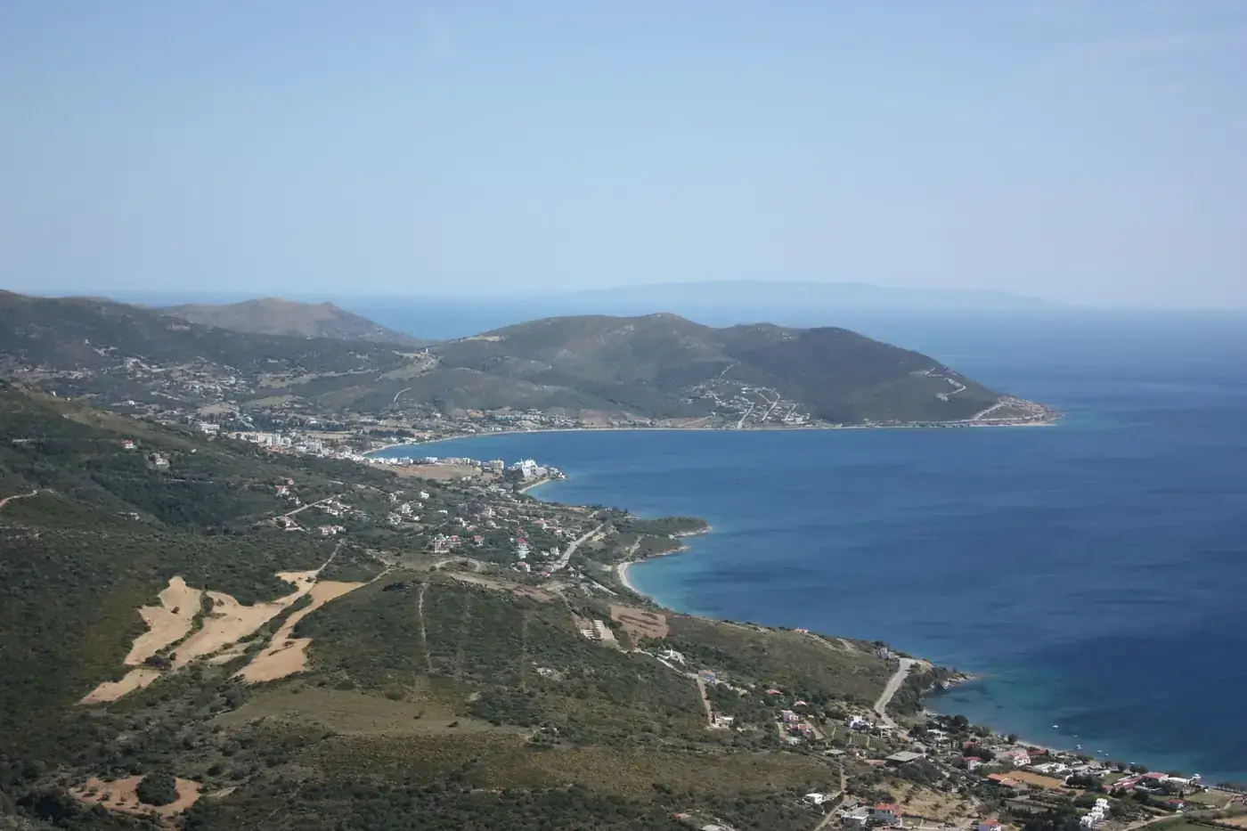 Aerial view of a serene coastline with blue sea and hills, perfect for nature enthusiasts.