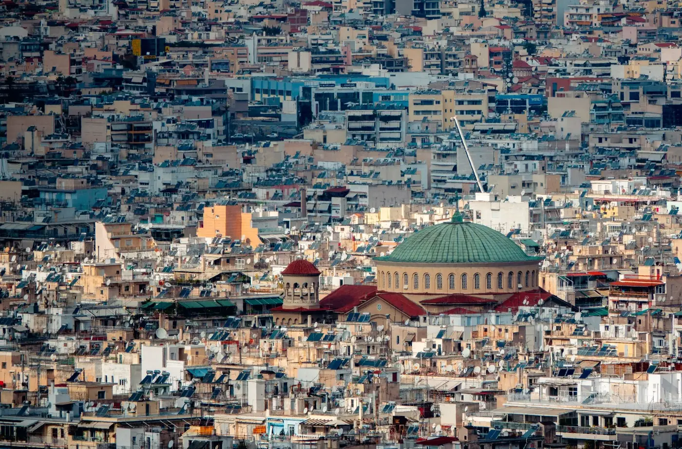 Explore the dense cityscape of Athens highlighting a prominent historic dome among the rooftops.
