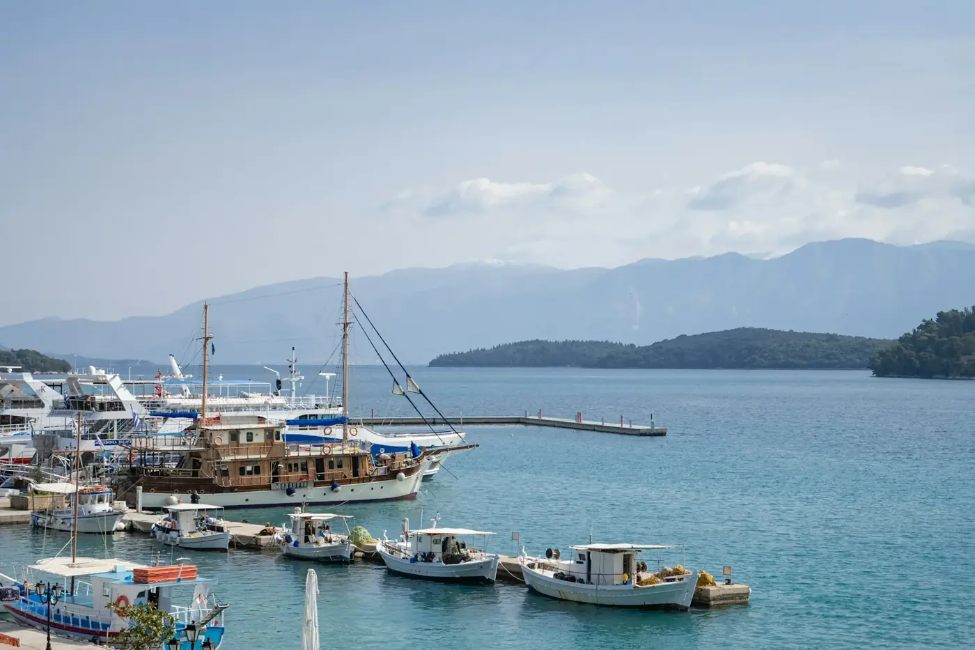 Boats docked in a calm harbor with distant mountains