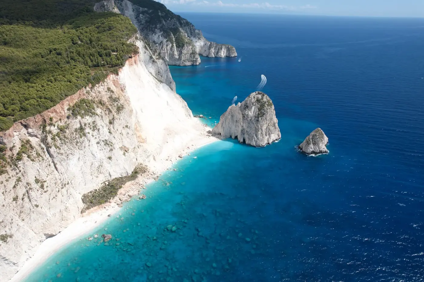 Breathtaking aerial view of rugged ocean cliffs and turquoise waters in a sunny summer setting.