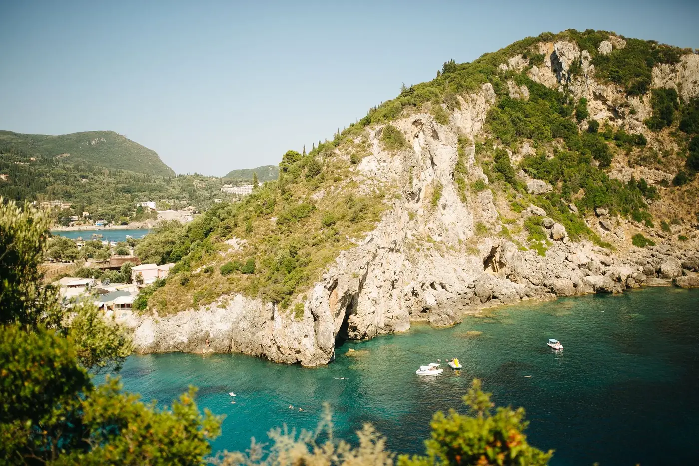 Beautiful coastal landscape with turquoise waters, boats, and rocky hillside, ideal for travel inspirations.