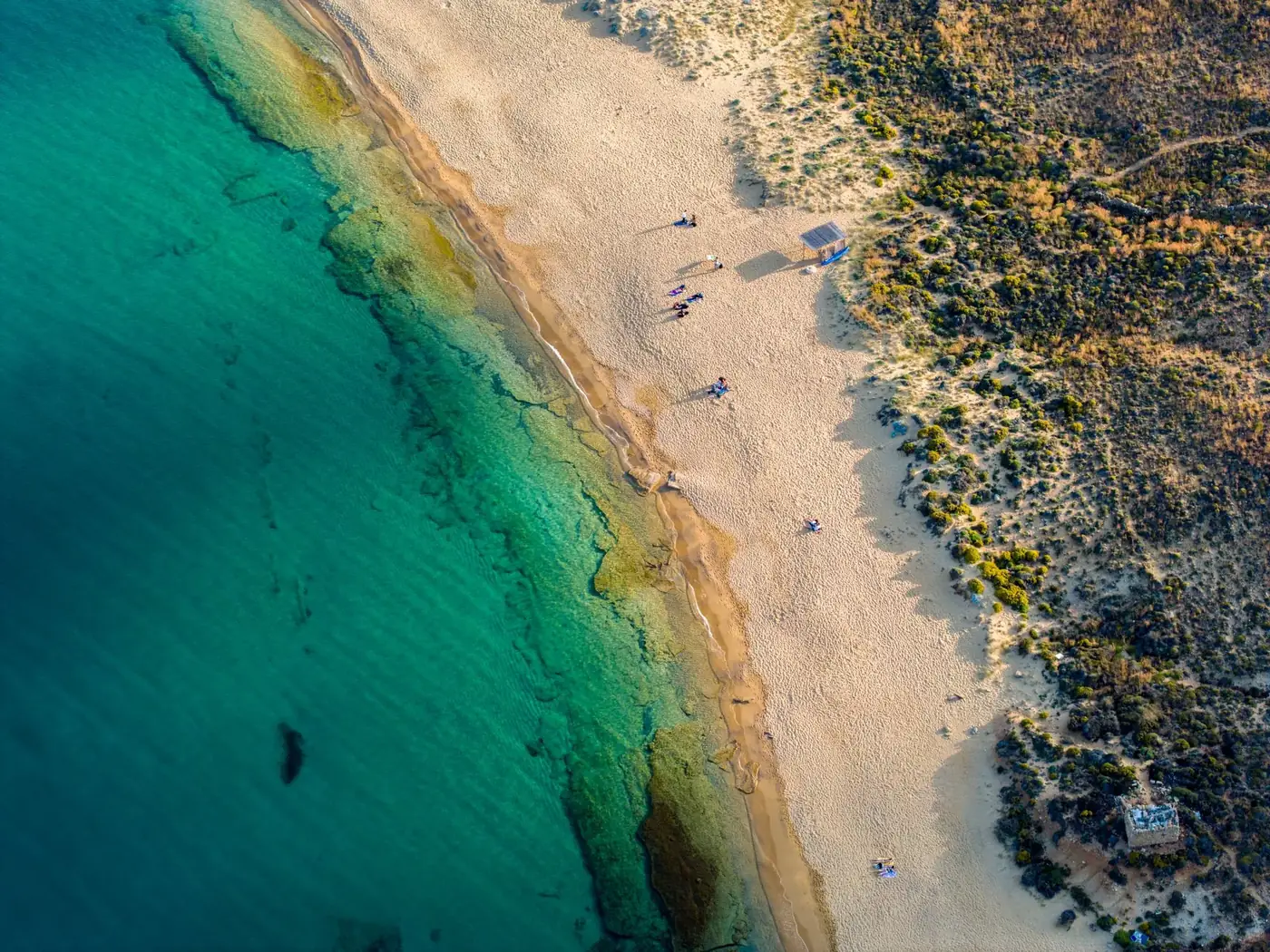 Stunning aerial view of a secluded sandy beach and turquoise waters in Greece showcasing natural beauty.