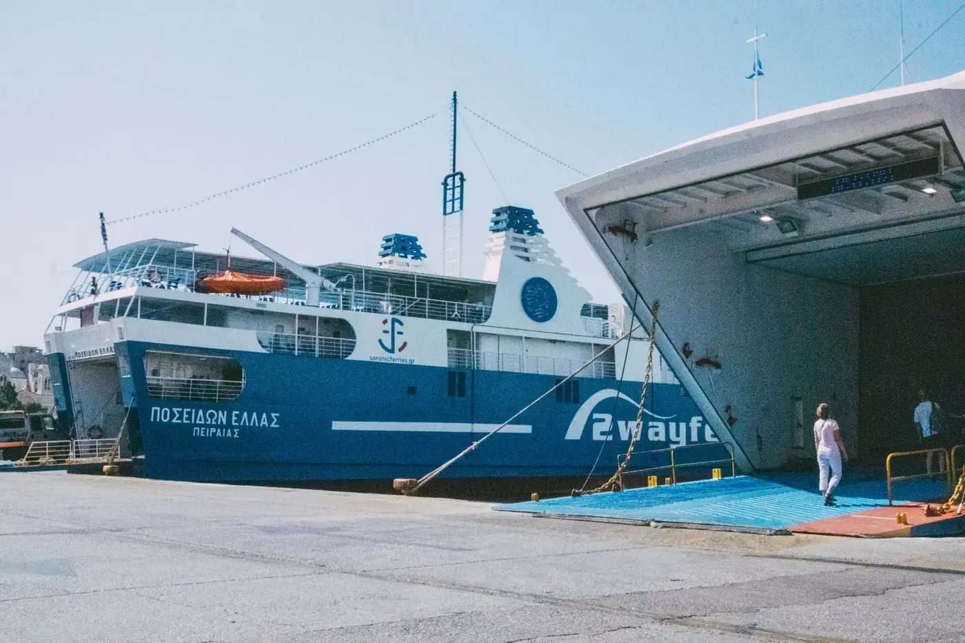 A large passenger ferry docked at a port with people boarding under a clear blue sky.
