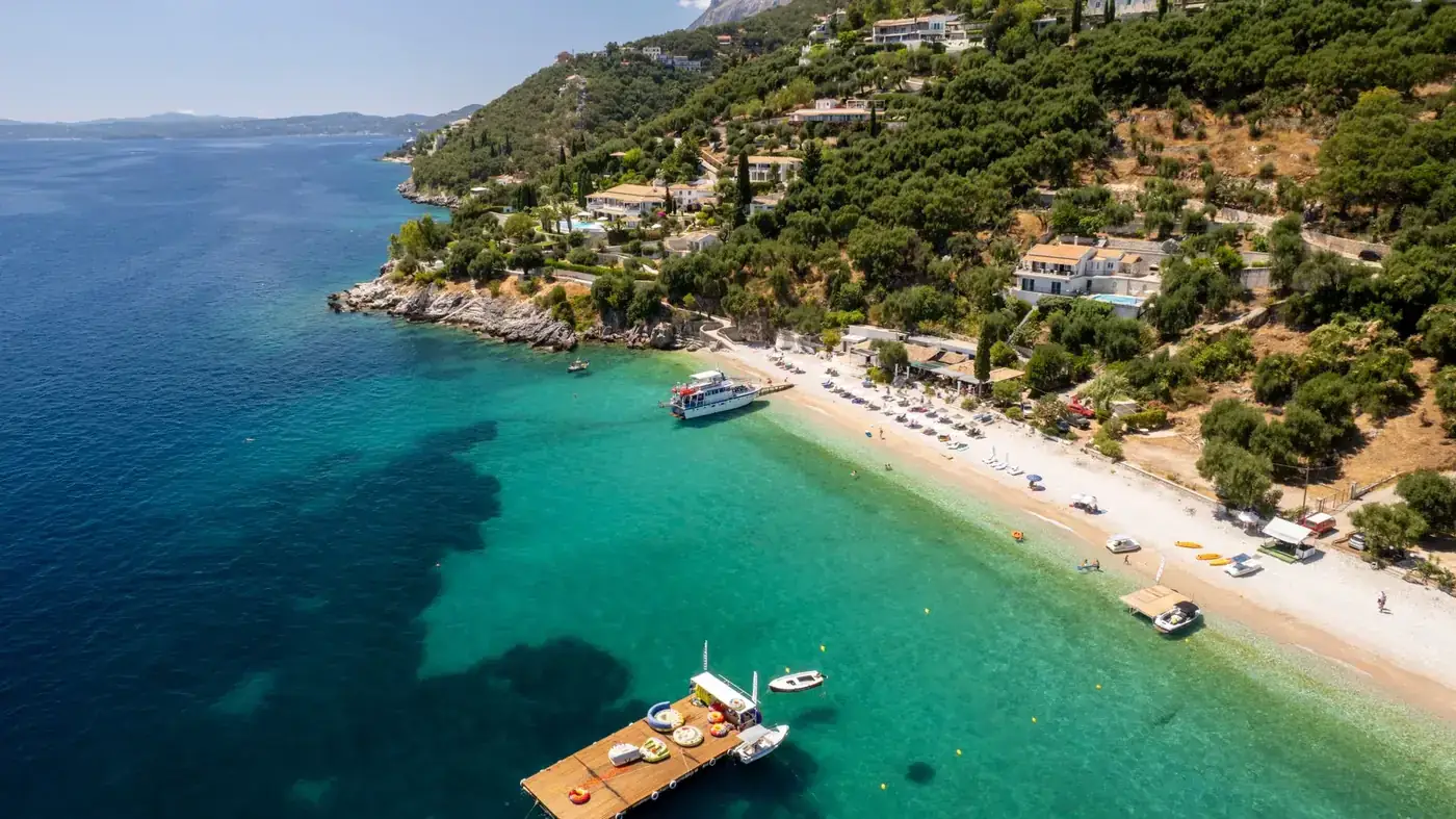 Stunning aerial view of a scenic coastline in Corfu, Greece featuring turquoise waters and lush greenery.