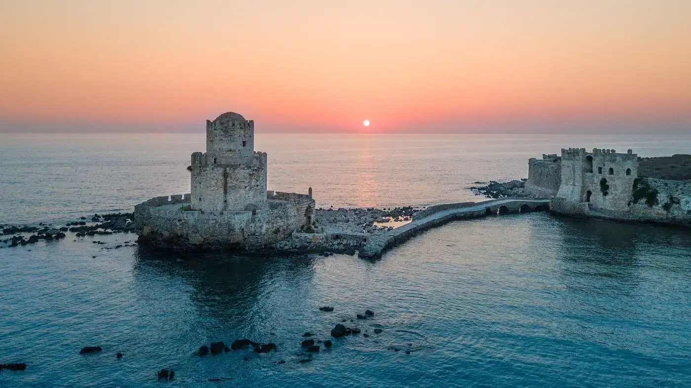 A stunning aerial view of Methoni Castle at sunset over the serene sea in Greece.