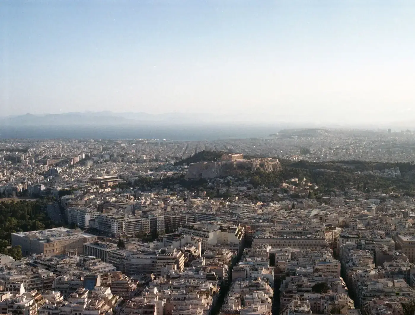 Stunning aerial view of Athens showcasing the Acropolis against a setting sun.