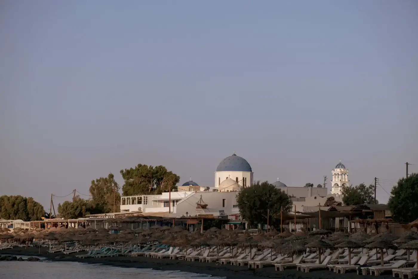 Capture of a serene beachfront with distinctive Mediterranean architecture at sunset.
