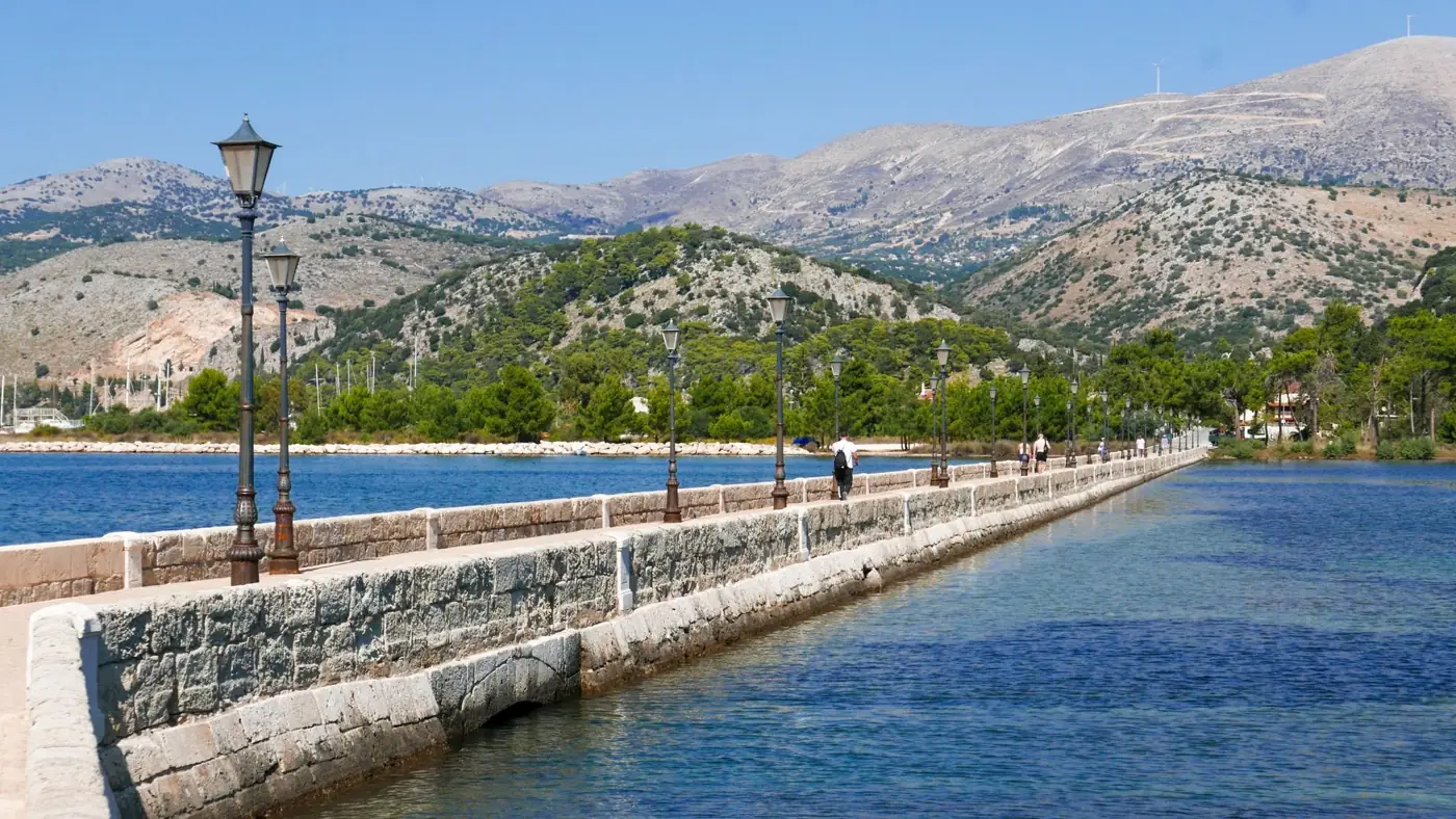 A picturesque stone walkway with lampposts spanning water in sunny Kefalonia, Greece.