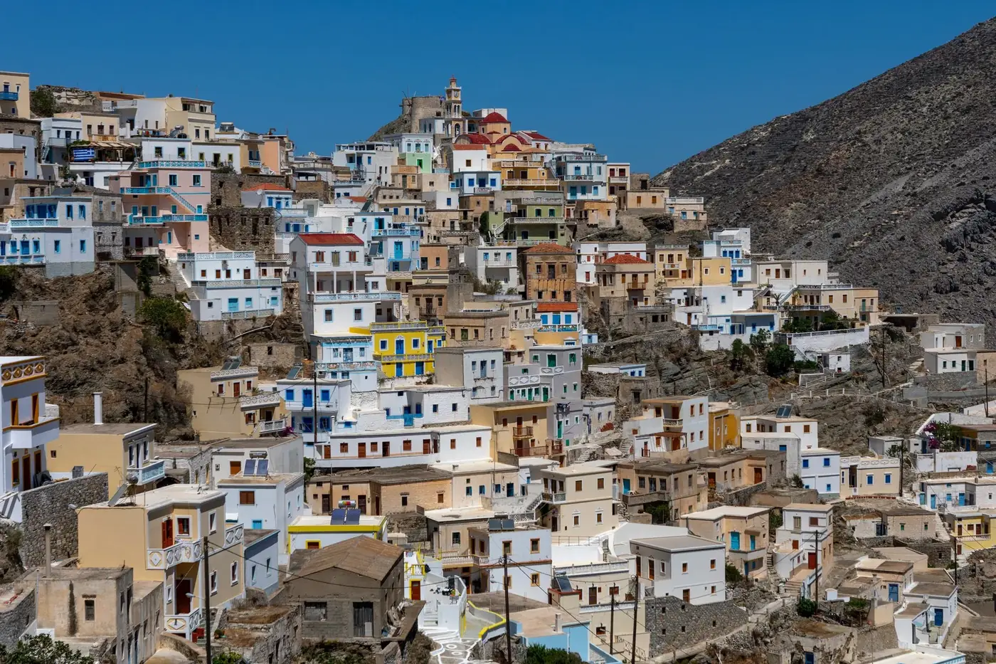 A vibrant view of traditional colorful houses on a hillside in Olympos, Greece.