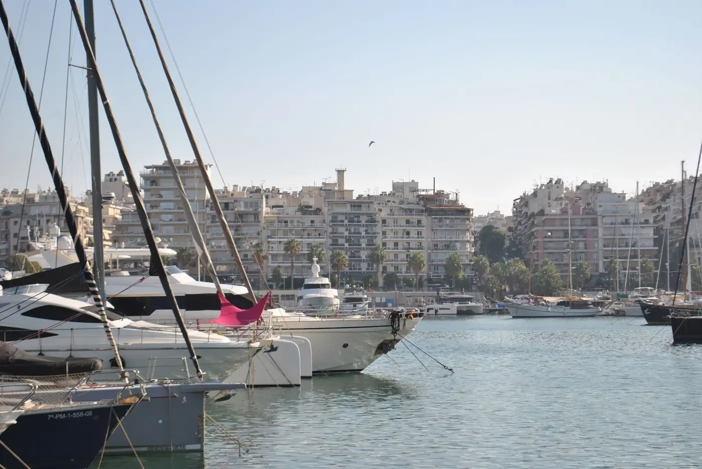 A picturesque view of a marina with luxury yachts docked against a vibrant urban backdrop.