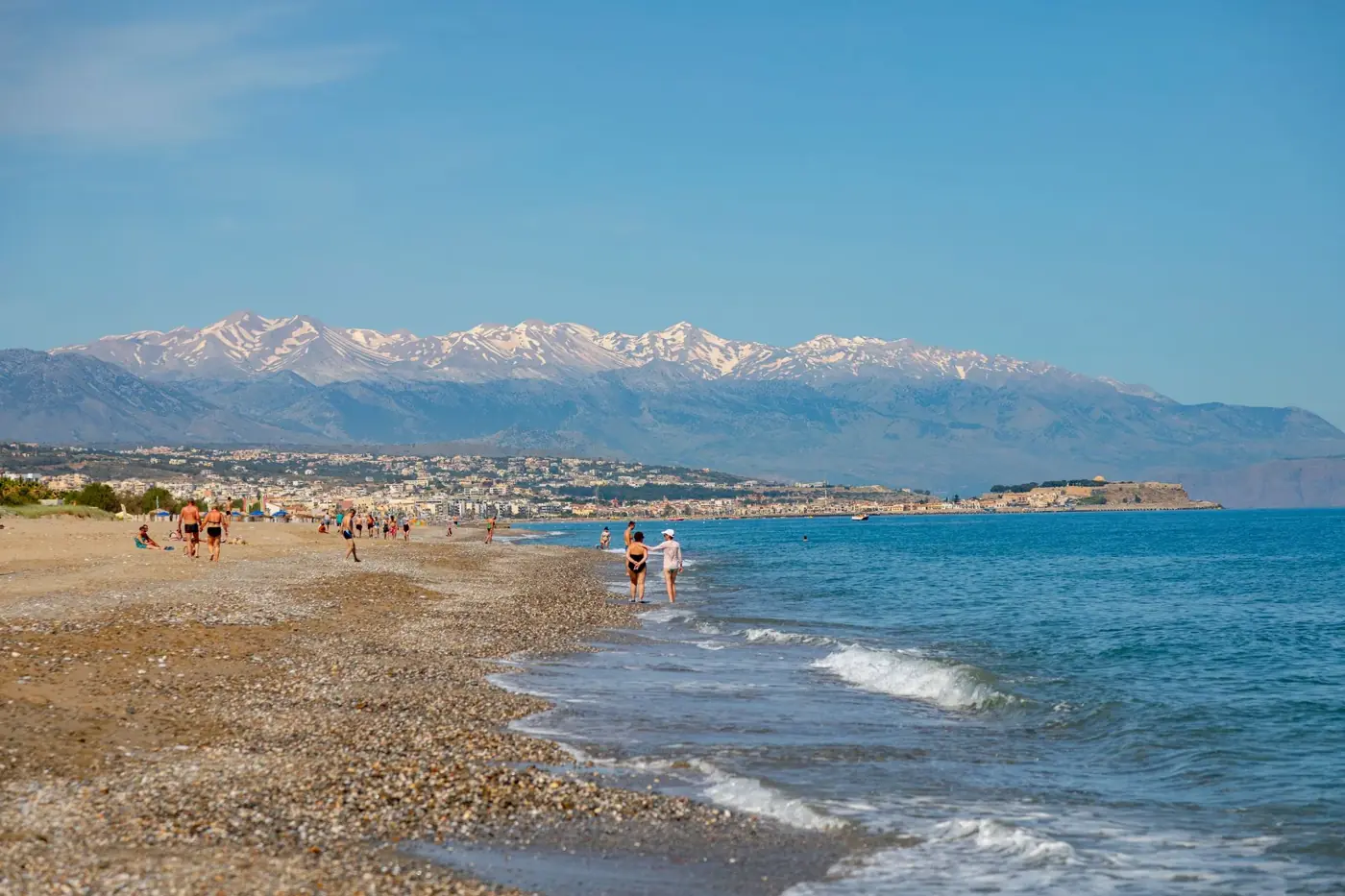 A beautiful beach in Crete, Greece with mountainous backdrop, showcasing clear blue skies.