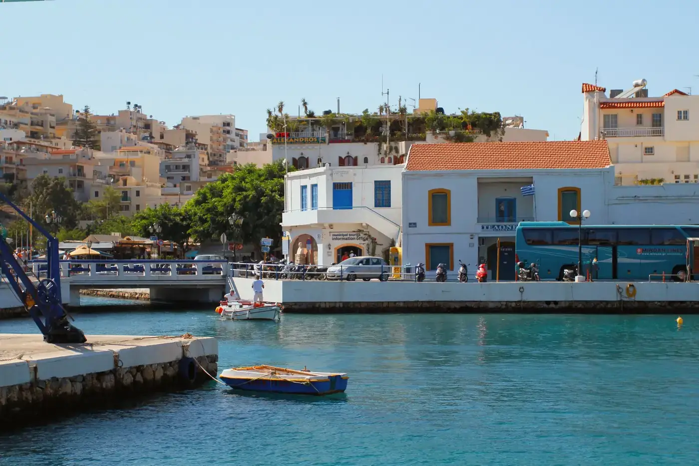 Vibrant waterfront scene in Agios Nikolaos, Crete, featuring a colorful boat and Mediterranean architecture.