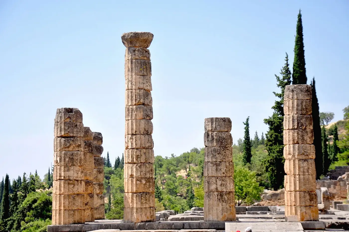 Explore the majestic ancient ruins of Delphi, Greece, highlighting historic columns against a clear sky.