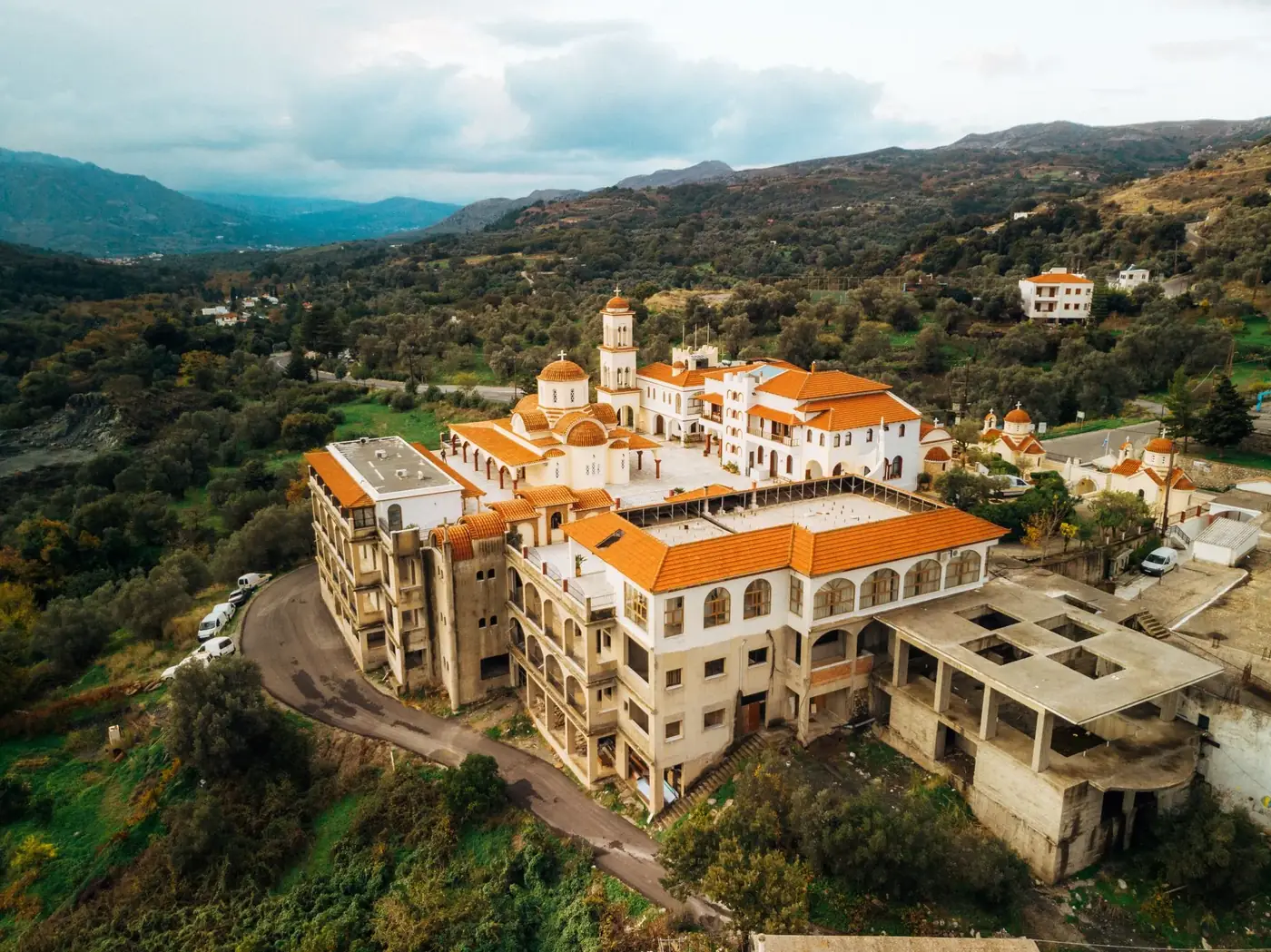 Discover a charming Greek village with traditional architecture nestled in lush green hills.