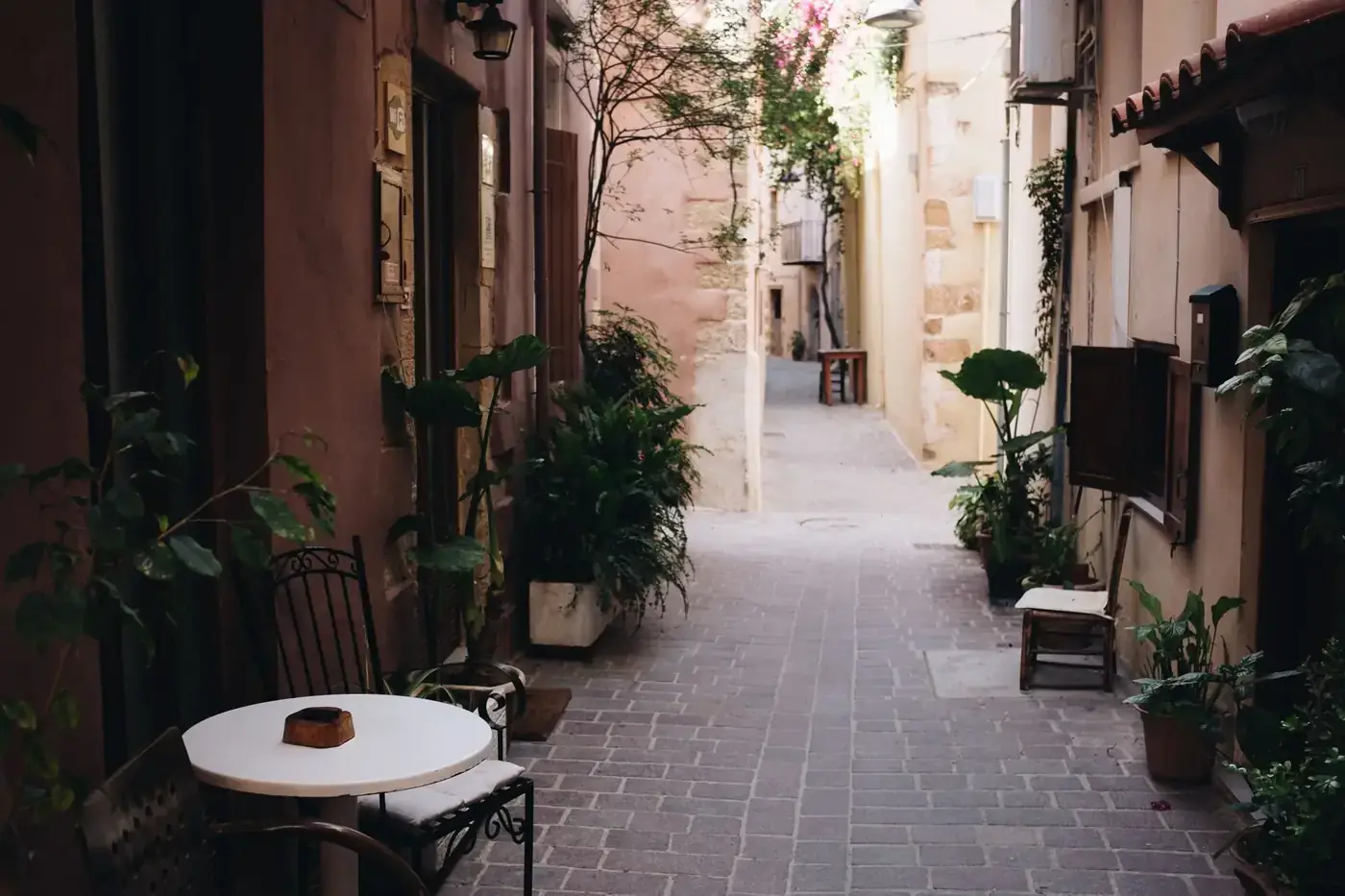 Picturesque alleyway in Chania with plants and outdoor seating, capturing the charm of Greek architecture.