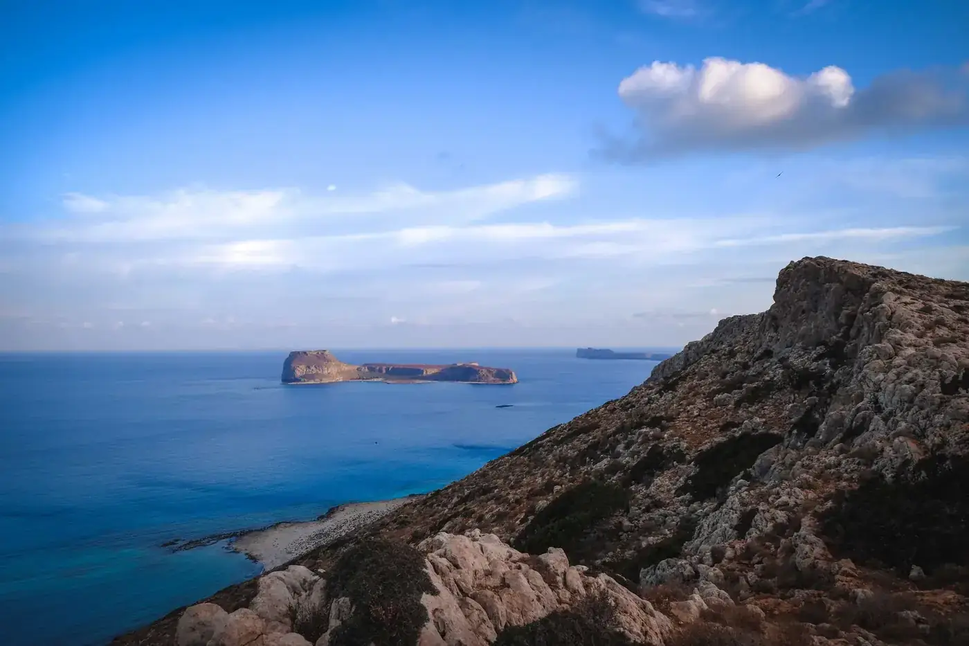 The scenic view captures a rocky coastline and serene ocean under a vibrant blue sky.