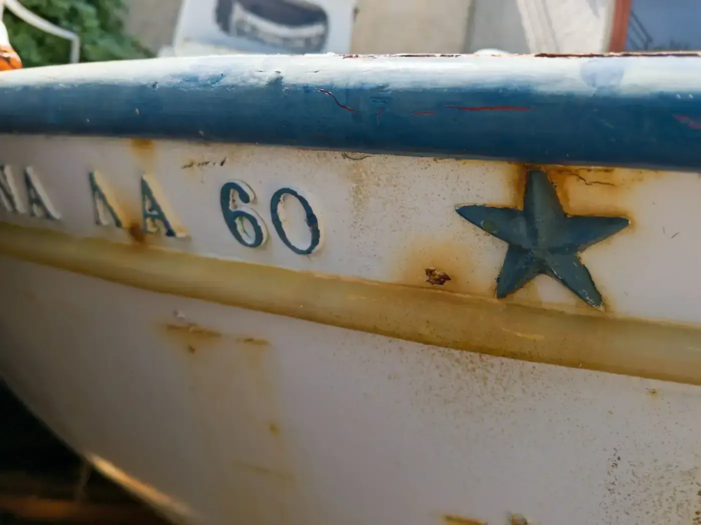 Detailed close-up of a weathered boat showing rust spots and a blue star motif.