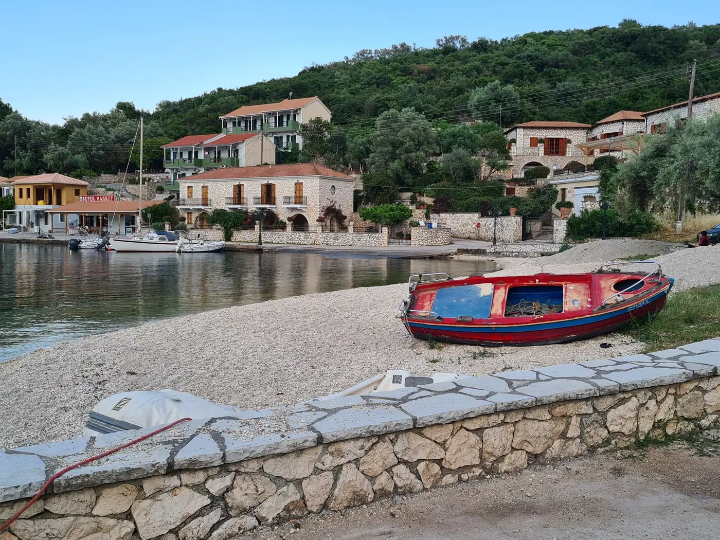 Charming Greek village with boats by a peaceful beach. Idyllic island setting.