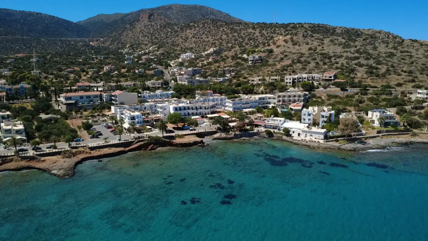 A stunning aerial view of the coastal town Stalída in Crete, Greece, showcasing hotels and turquoise waters.