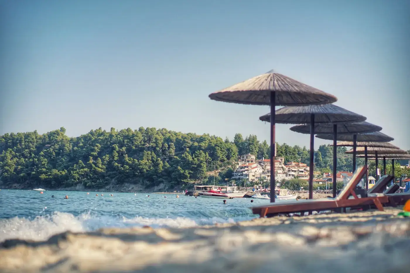 Tranquil beach with straw umbrellas and a beautiful sea view under a clear sky.