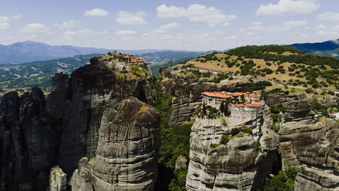 Stunning aerial shot of Meteora monasteries perched on rocky cliffs in Greece's landscape.