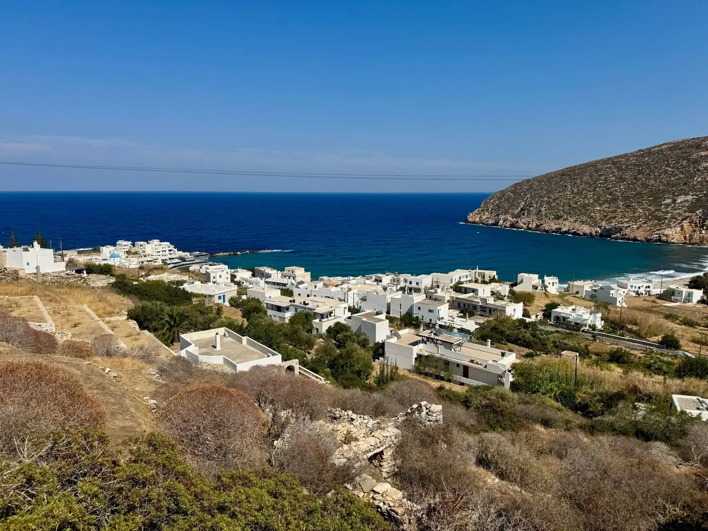Stunning view of a Cycladic village by the sea with blue waters and white buildings.