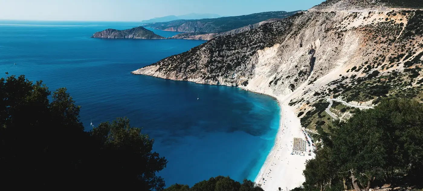 Discover the breathtaking aerial view of Myrtos Beach in Greece with turquoise waters and surrounding cliffs.