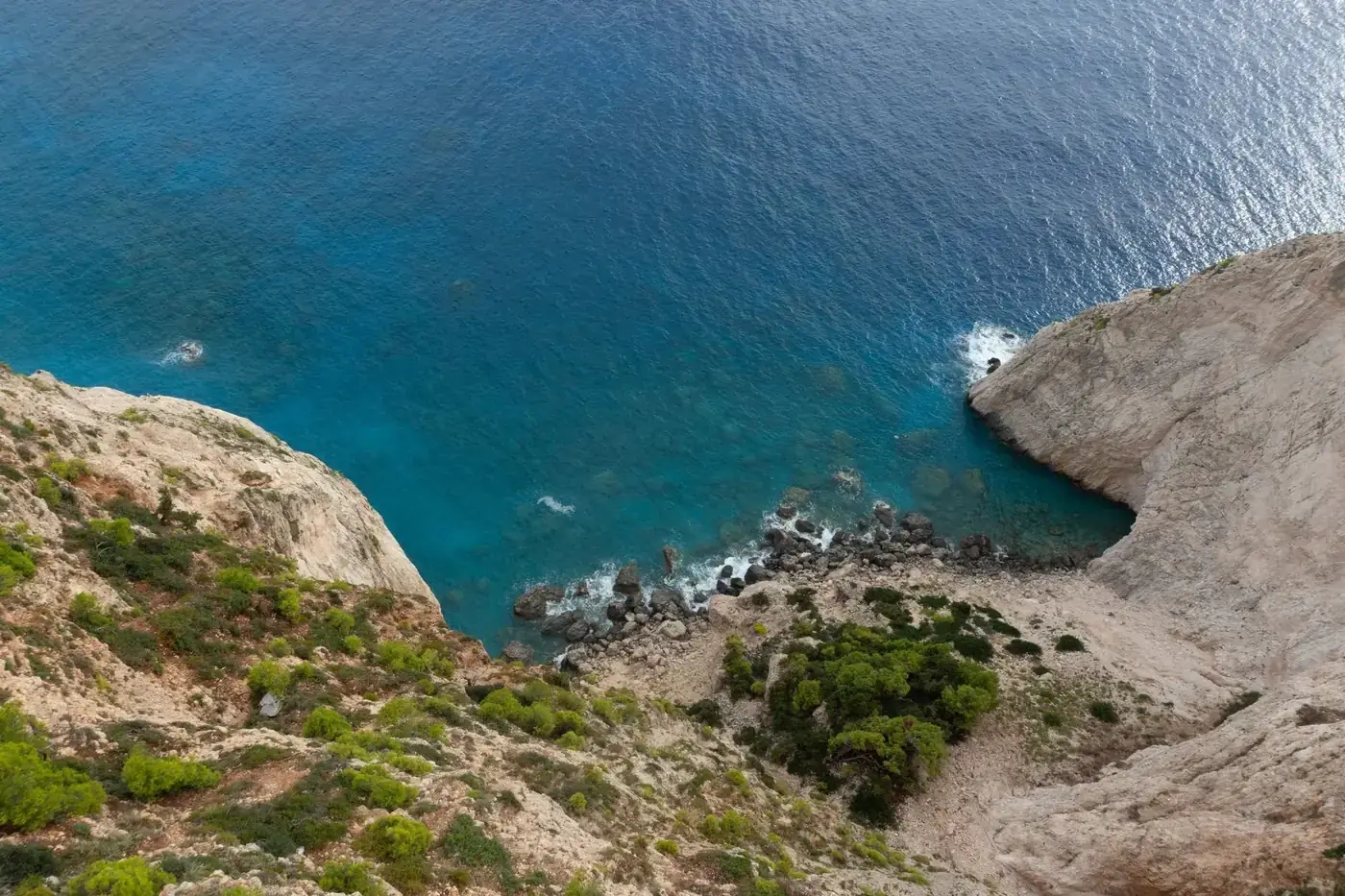 Stunning aerial view of Zakynthos coastline with clear blue sea and rugged cliffs.