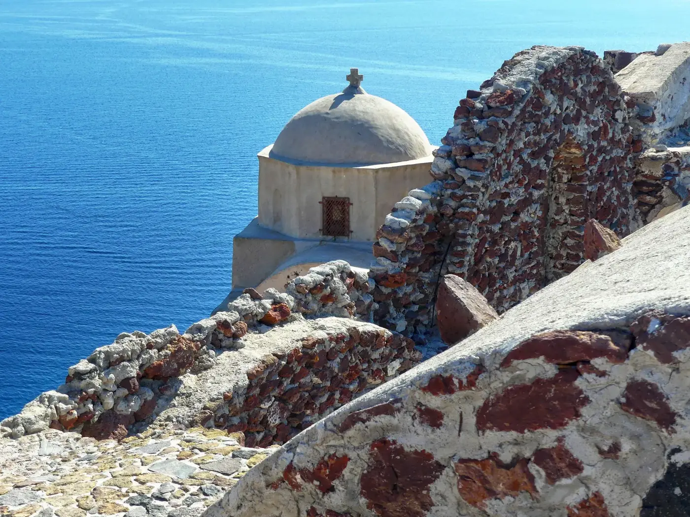 Captivating view of a dome and stone walls overlooking the Aegean Sea in Santorini, Greece.
