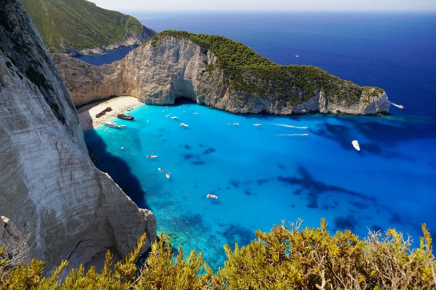 A stunning overhead view of Navagio Beach, showcasing its turquoise waters, sandy shore, and surrounding cliffs in Greec